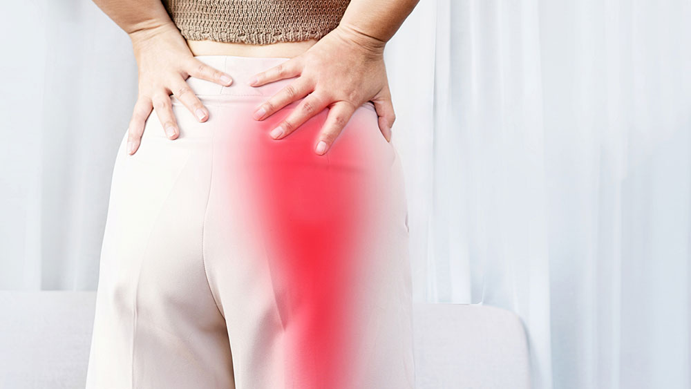 Woman suffering from sciatica pain, causing pain in the buttocks, which spreads down the leg