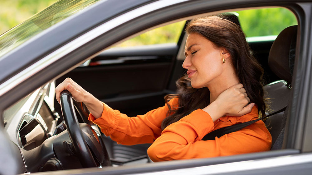 Whiplash Injuries: More Than Just a Pain in the Neck Young woman in her car suffering from a whiplash injury